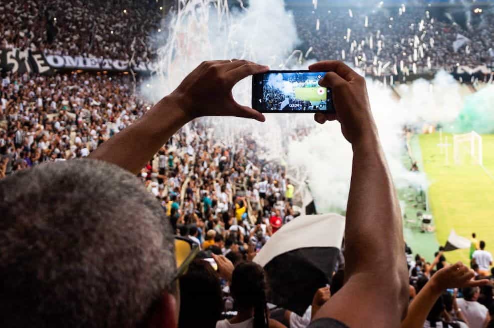 Penggemar sepak bola menonton perayaan pertandingan di stadion.