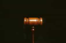A wooden gavel sits on a black surface.