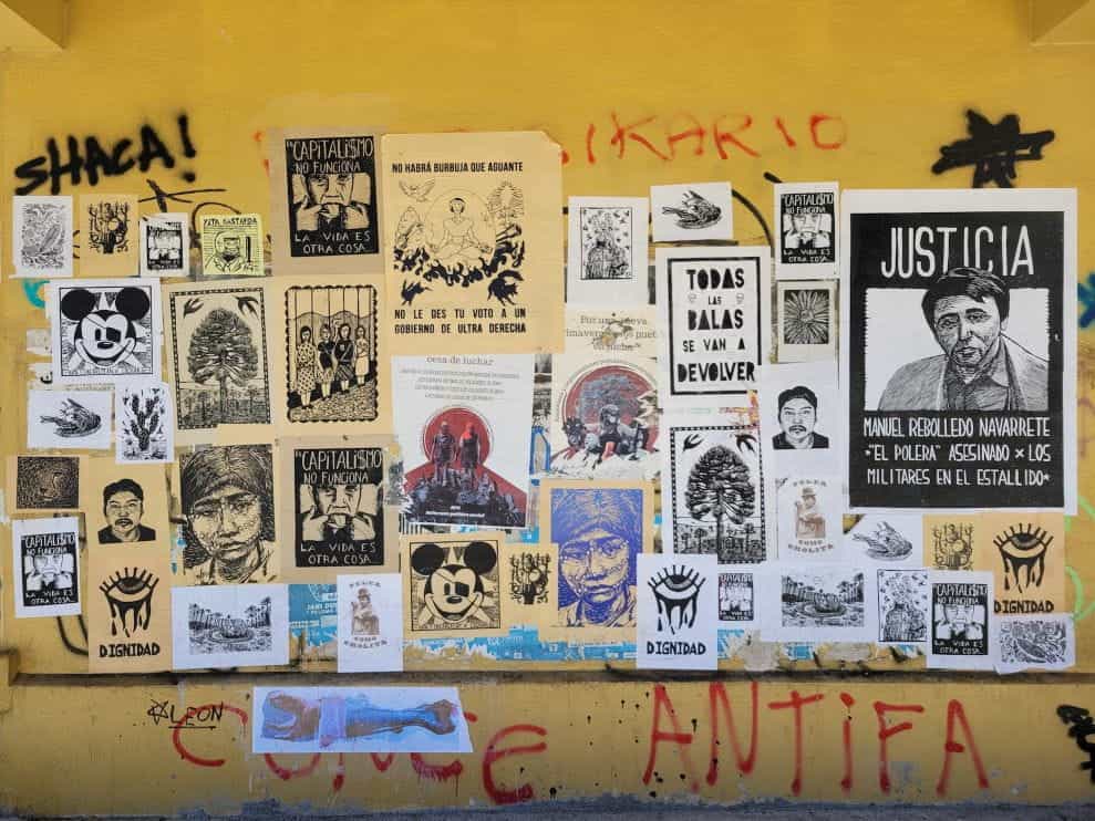 Berbagai poster dan grafiti di dinding kuning di Concepción, Chili.