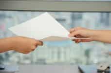 A person handing a document to another person.