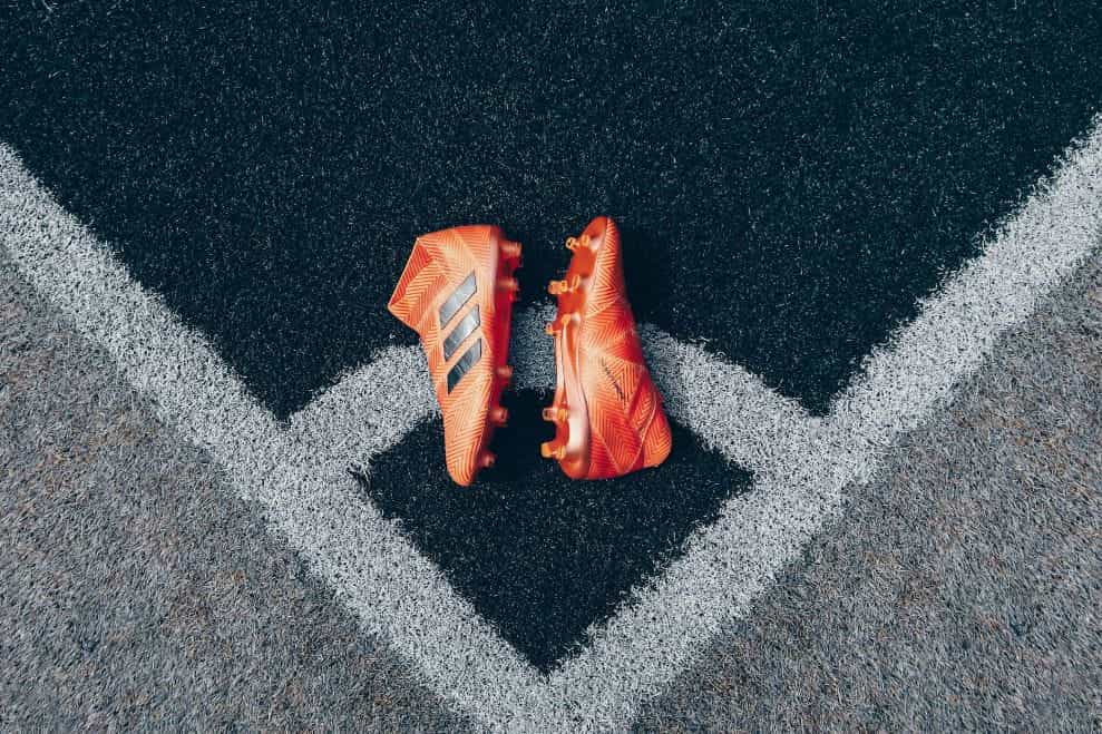A pair of orange football boots placed near the corner flag.
