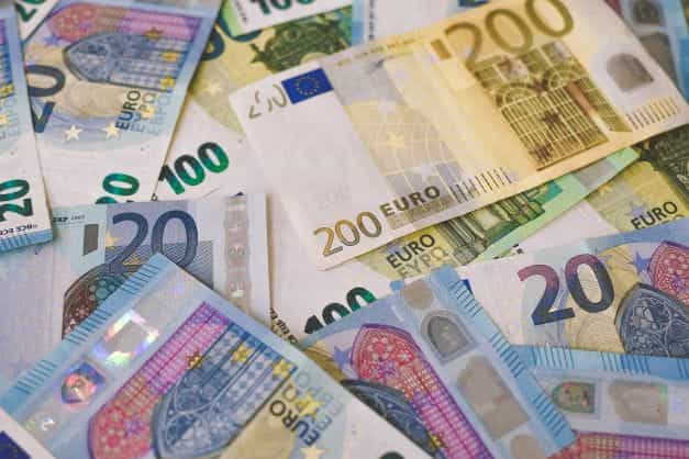 Uang kertas Euro dari berbagai denominasi tersebar di permukaan datar.