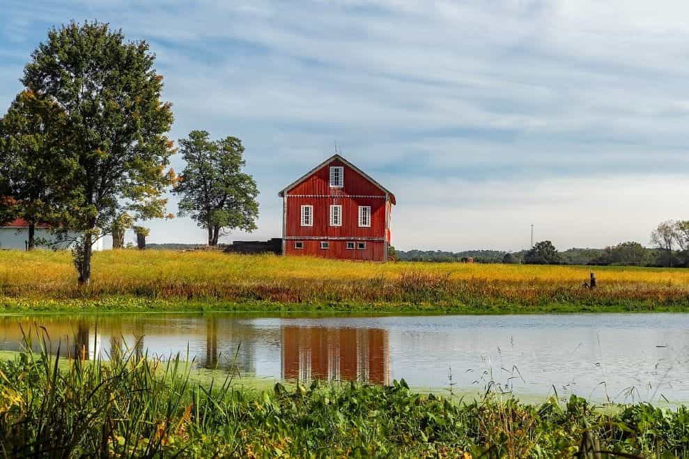 A small red barn in front of a small pond on a rural farm in the state of Ohio in the United States.
