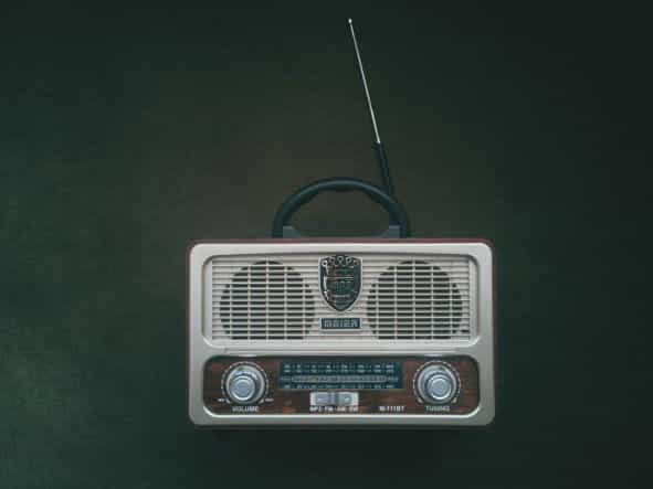 Pemutar radio berwarna putih dan coklat ditempatkan dengan latar belakang hijau.