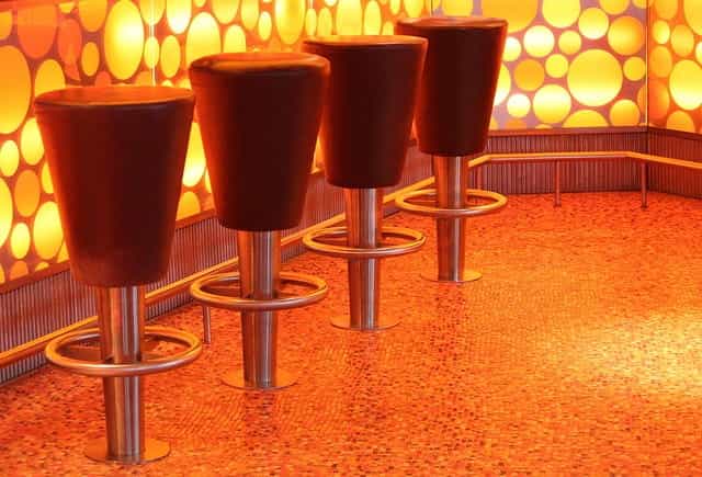 Empat kursi bar tetap di sebuah bar dengan desain pola menyala di sepanjang sisi bar.