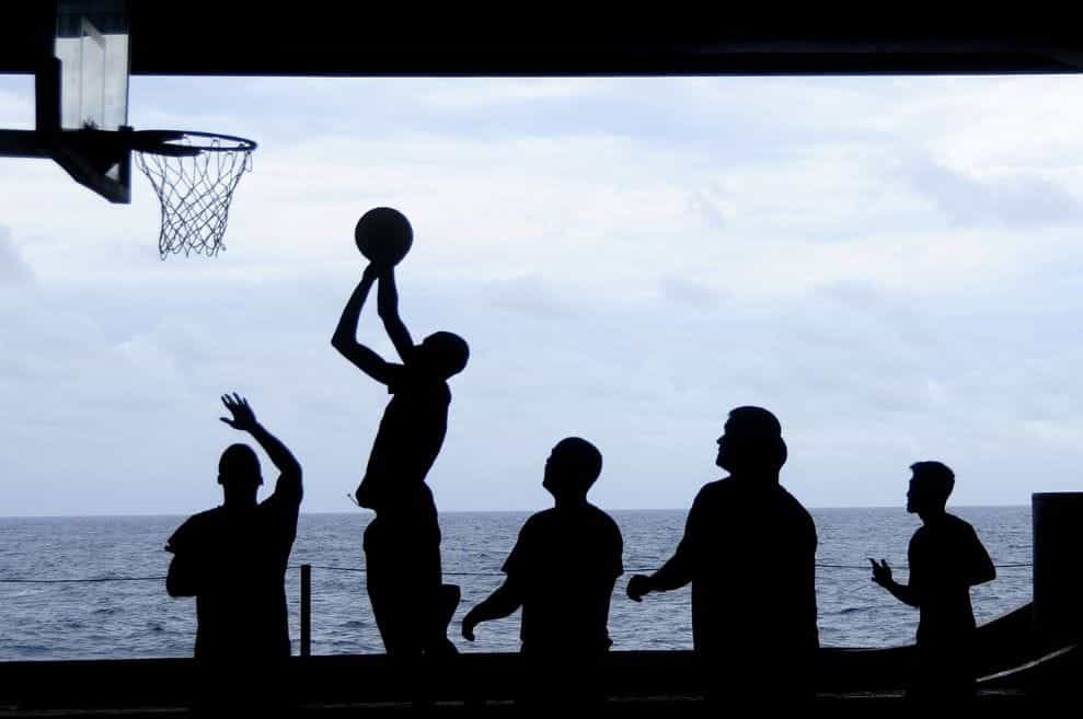 Siluet hitam dari sekelompok orang yang sedang bermain bola basket.