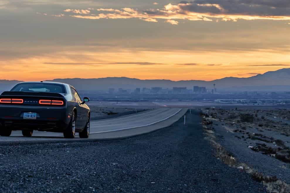 Ford Mustang hitam melaju di jalan kosong di gurun Nevada.