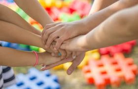 Several people’s hands coming together in unison in a sign of friendship.