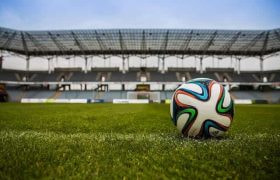 A football on a grass pitch in a stadium.
