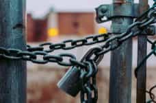 A heavy lock and chain keep a gate closed.