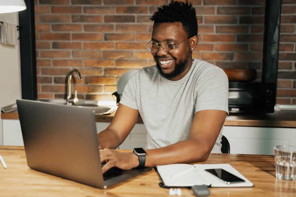 A man using a laptop in the kitchen.