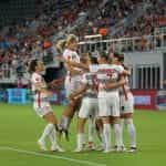 A women’s soccer team celebrates during a game.