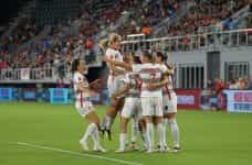 A women’s soccer team celebrates during a game.