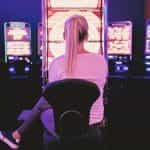 A woman sitting in front of a series of casino video betting machines.