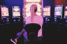 A woman sitting in front of a series of casino video betting machines.