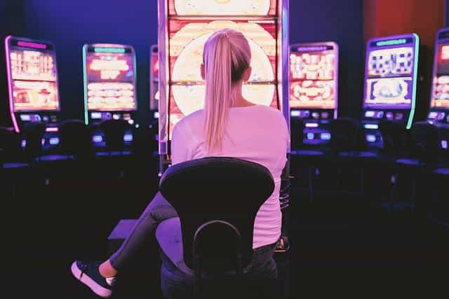 Seorang wanita duduk di depan serangkaian mesin taruhan video kasino.