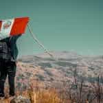 A man carries a Peruvian flag behind his back on a mountain.