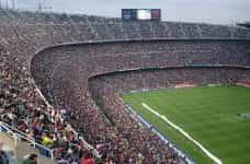 A huge sports stadium filled to the brim with spectators watching a large-scale sporting event.