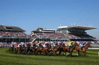 A general view of horses and riders taking the first bend at Aintree Racecourse.