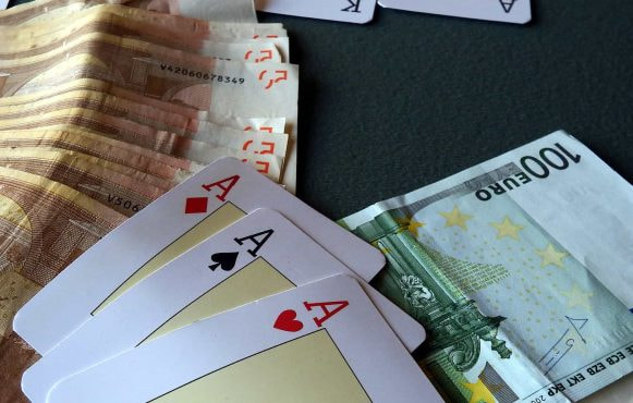 Three aces and a pile of cash on a poker table.