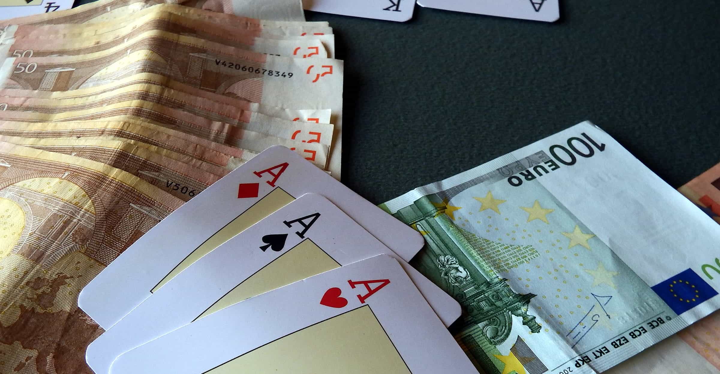 Tiga ace dan setumpuk uang tunai di atas meja poker.