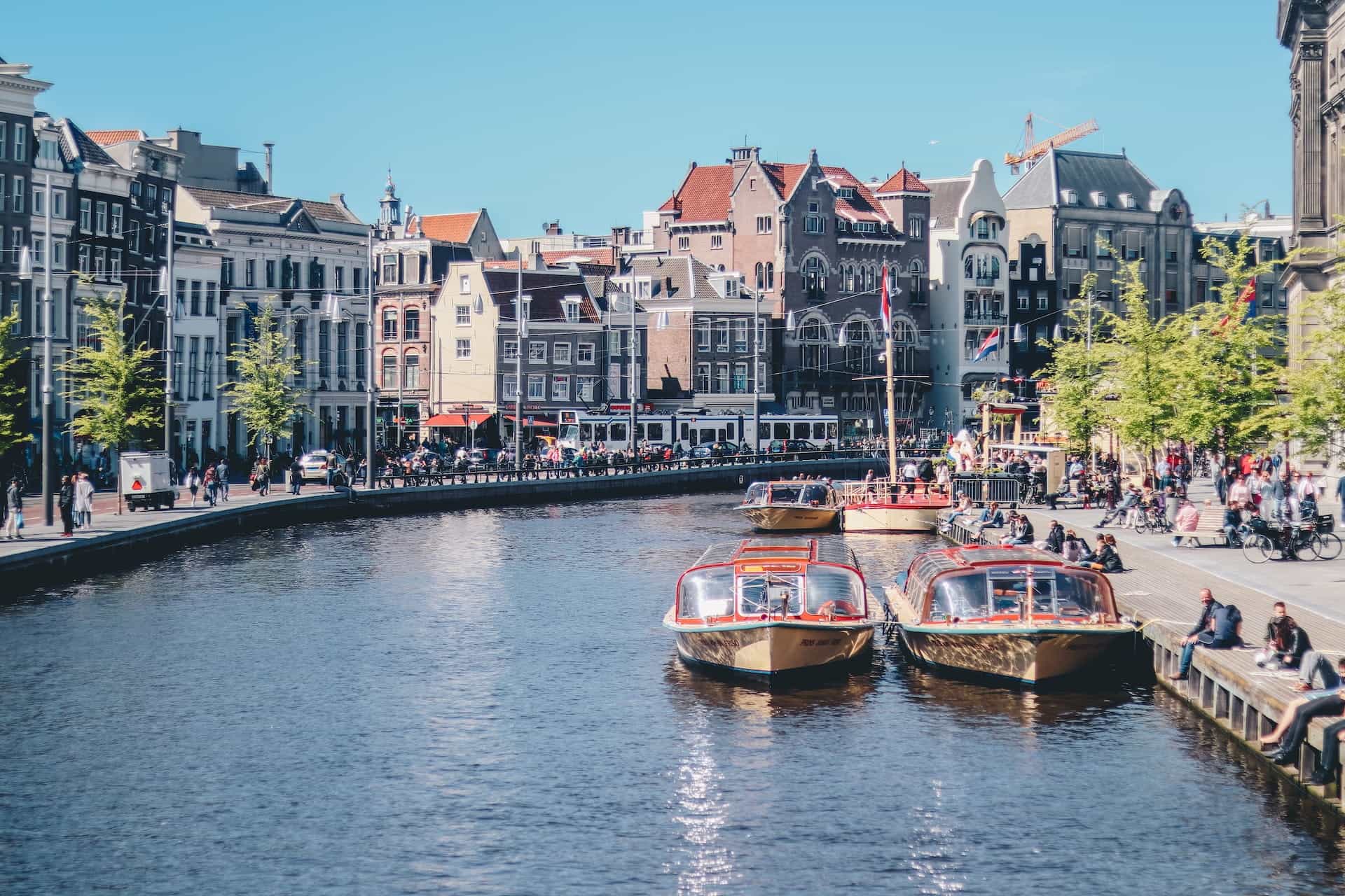 Kanal Amsterdam dengan dua perahu terlihat di air.