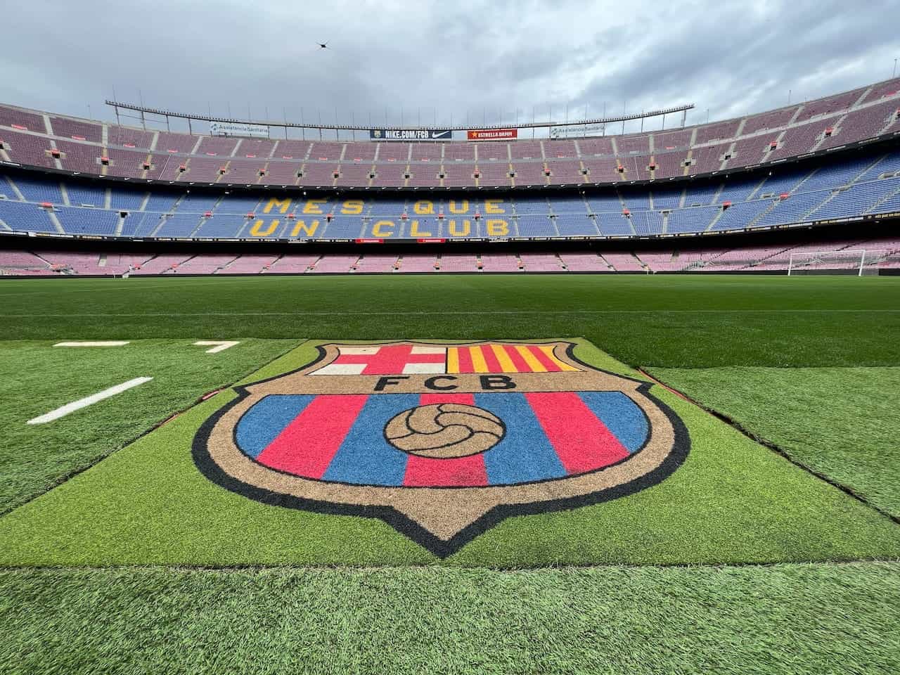 FC Barcelona logo on grass pitch in Camp Nou Stadium.