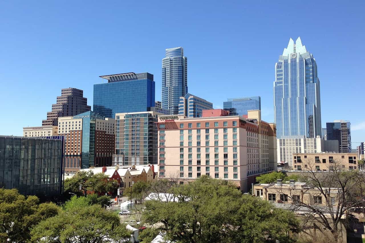 Sekelompok gedung tinggi dan gedung pencakar langit yang terletak di pusat kota Austin, Texas, dikelilingi oleh gedung-gedung yang lebih pendek dan kantong-kantong pepohonan dan tanaman hijau.