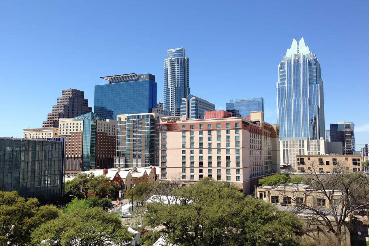 A cluster of tall buildings and skyscrapers located in downtown Austin, Texas, surrounded by shorter buildings and pockets of trees and greenery.
