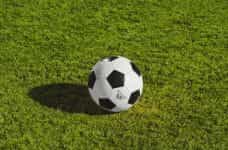 A soccer ball on a bright green grass soccer field.