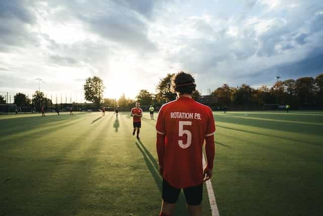 Pria berdiri di sekitar lapangan olahraga dengan kaus.