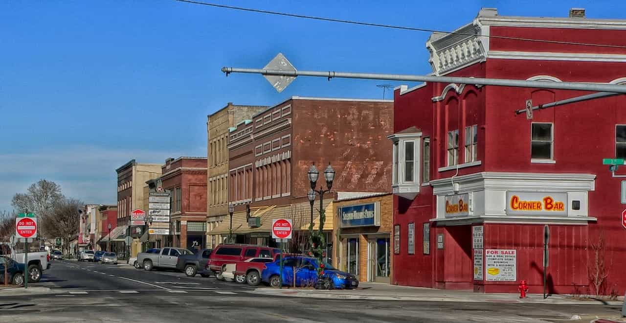 Main street in downtown Fremont, Nebraska, featuring several red-brick buildings and businesses lining the street, with several cars parked in front of them.
