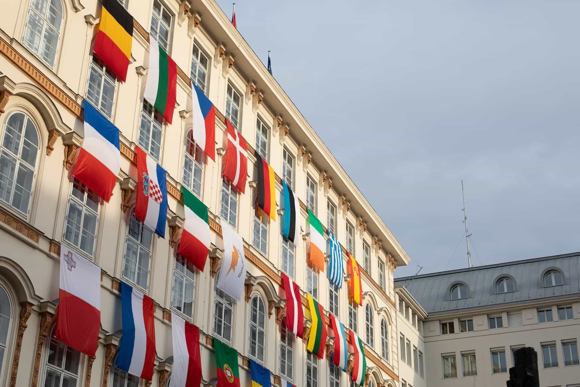 An old building with many different flags on its outside wall.