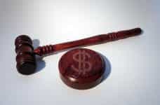 A wooden hammer lying next to a wooden gavel with a big dollar sign imprinted on it.