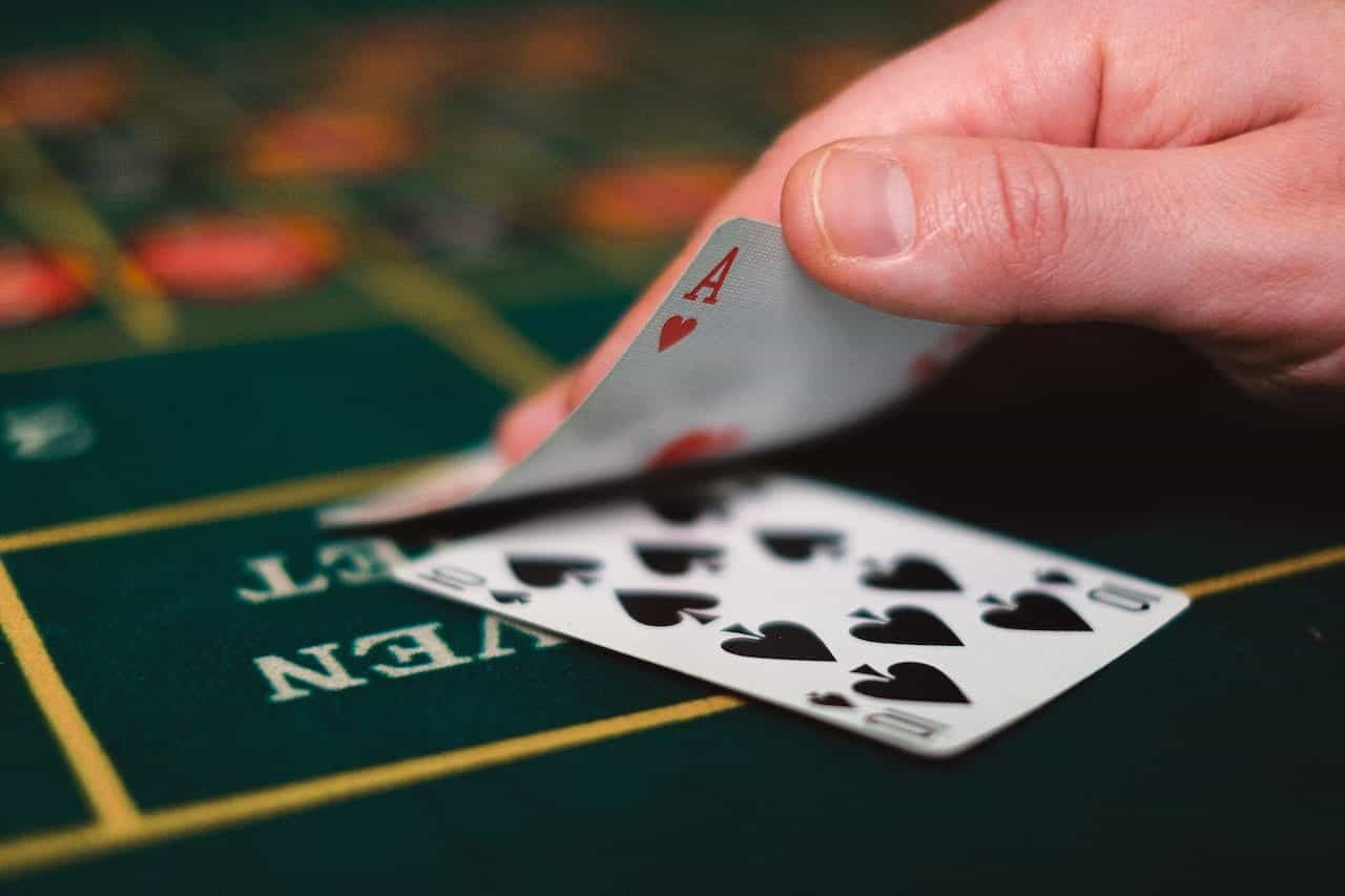 A hand holding playing cards in a casino.