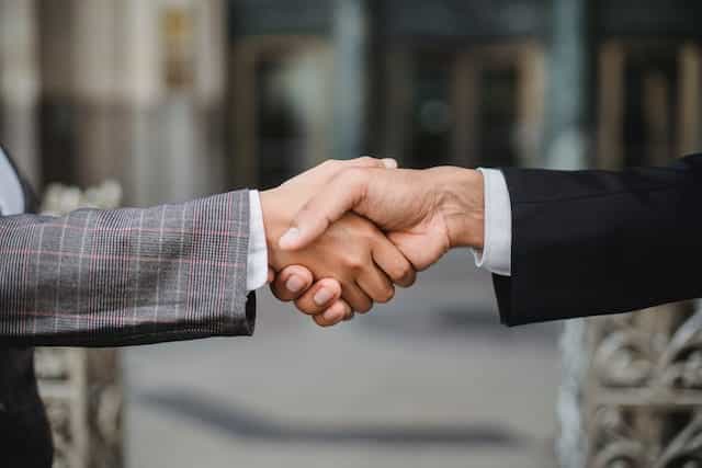 Dua orang bisnis berjabat tangan pada kesepakatan.