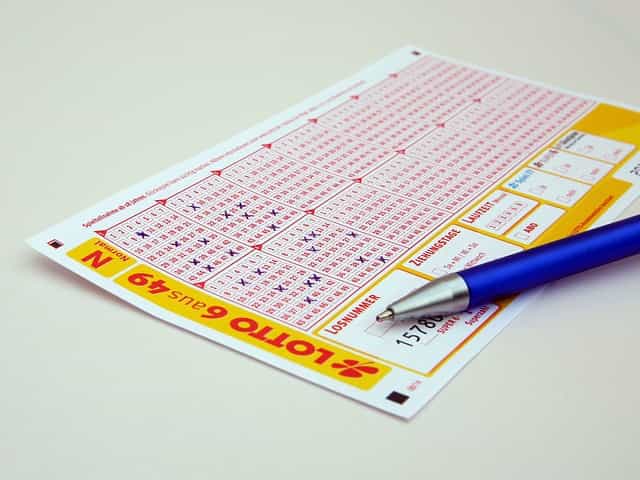Kartu remi lotre tergeletak di atas meja dengan pena diletakkan di atasnya.