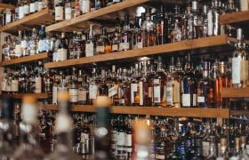 Shelves of liquor bottles lined up behind a bar.
