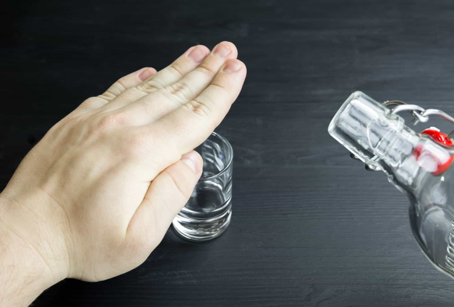 Sebuah tangan dipegang di atas gelas, mencegah lebih banyak vodka dituangkan ke dalamnya. 