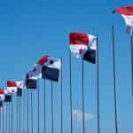 A row of flagpoles each with the Panamanian flag, waving in the wind.