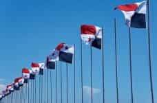 A row of flagpoles each with the Panamanian flag, waving in the wind.