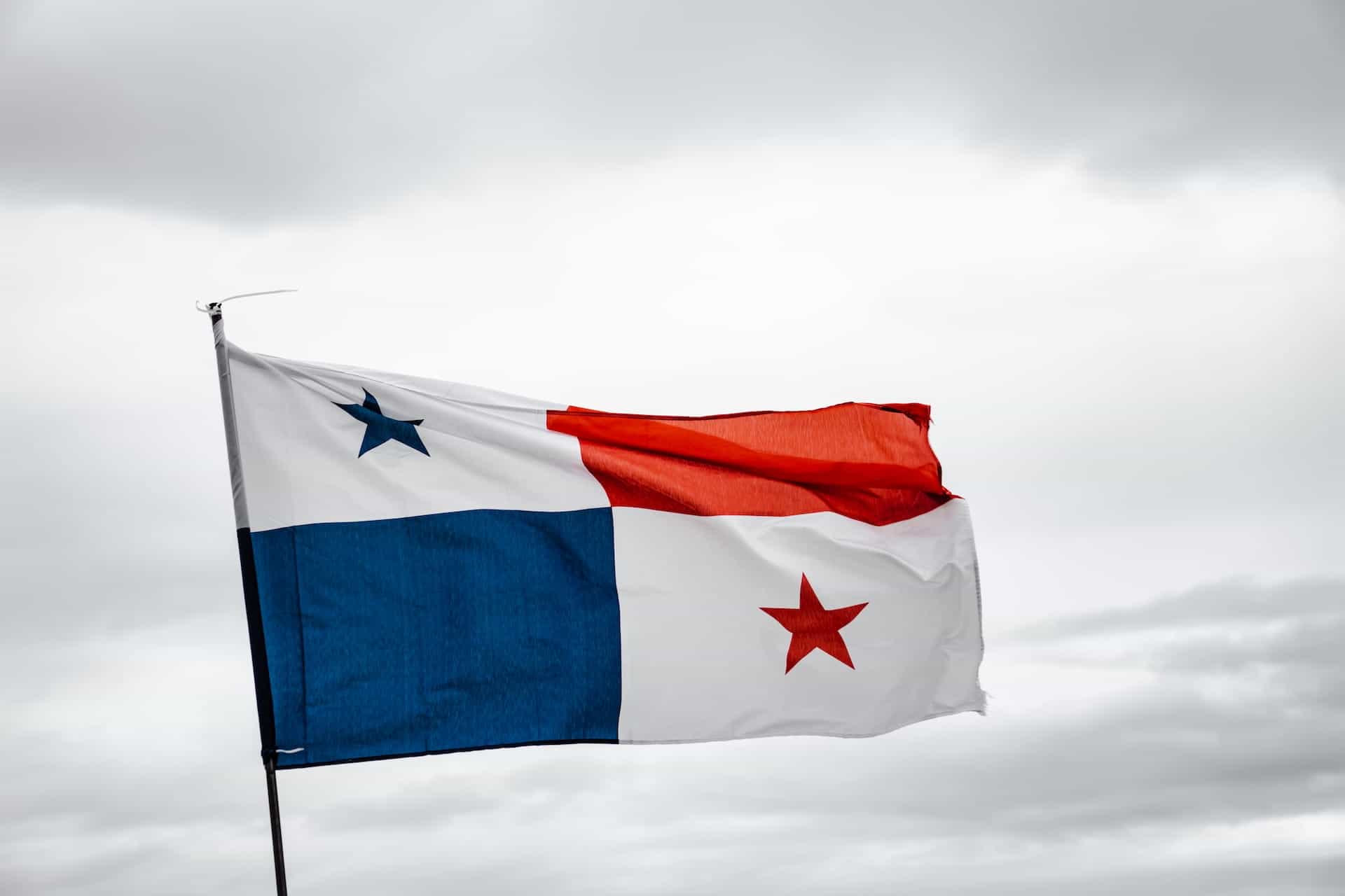 A Panamanian flag waves in front of a cloudy, gray sky.