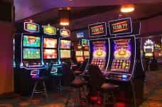 Several brightly lit slot machines in a casino room.