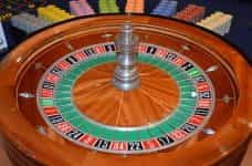A roulette wheel surrounded by colorful betting chips.