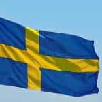 The Swedish flag fluttering against a blue sky.