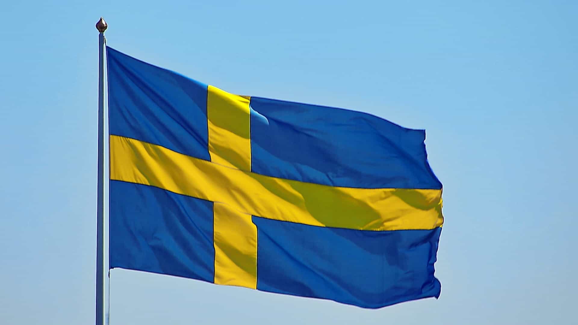 Bendera Swedia berkibar di langit biru.