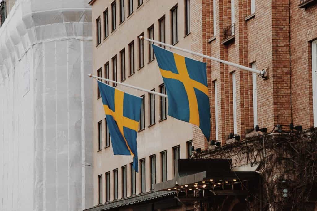 Dua bendera Swedia tergantung dari tiang di sisi sebuah bangunan.