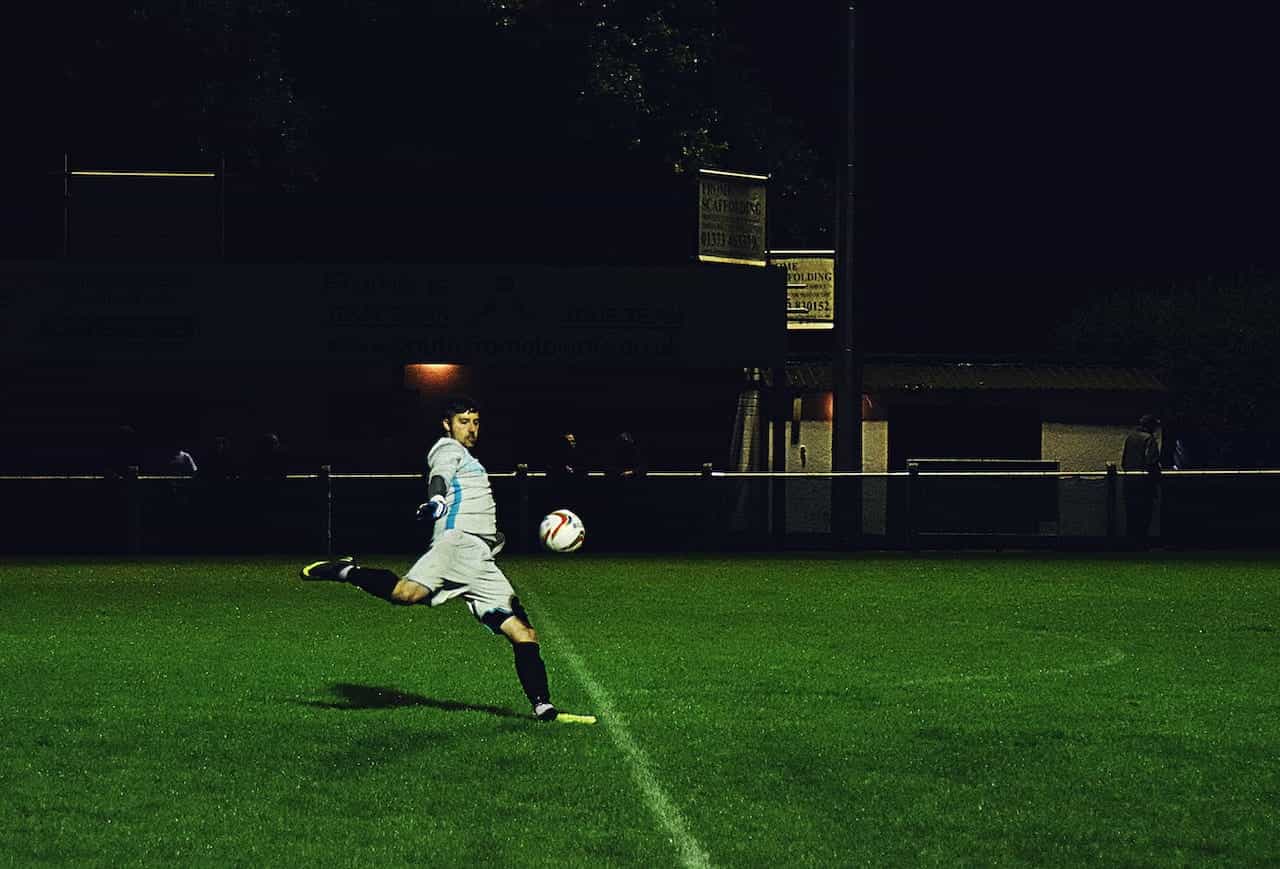 A footballer kicking a ball on a pitch.