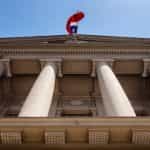 The Chilean flag waves over a government building with a facade of large columns.