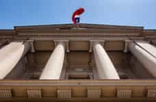 The Chilean flag waves over a government building with a facade of large columns.